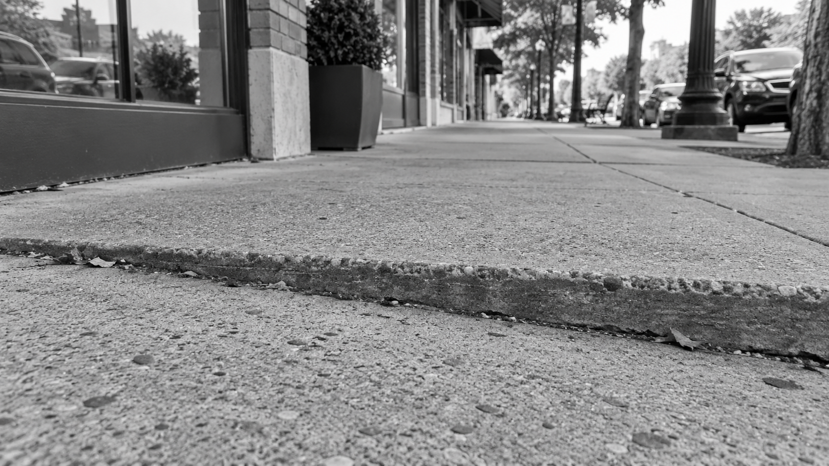 Uneven sidewalk joint outside a row of commercial storefronts