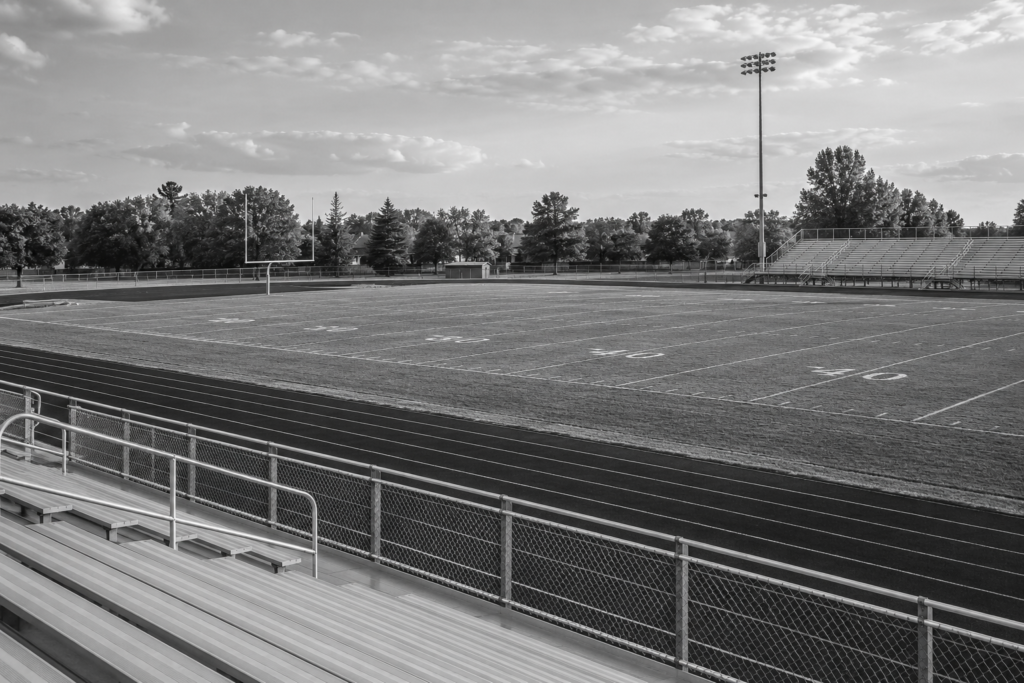 Empty high-school football game field and spectator bleachers