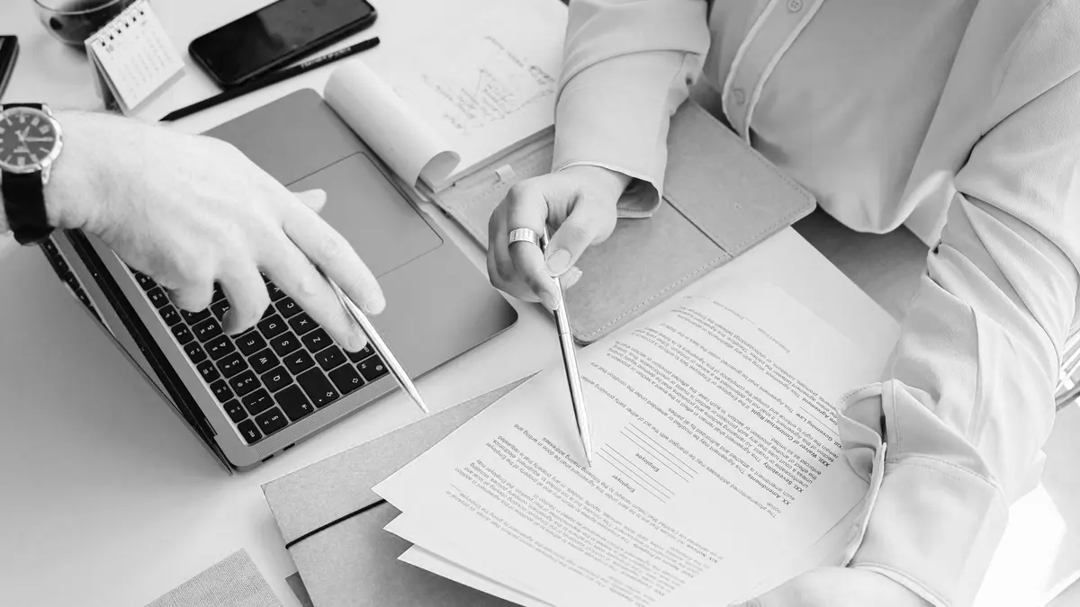 Hands reviewing an agreement on a desk
